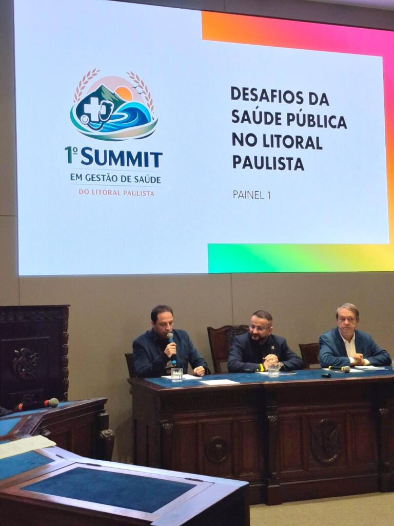 Mesa de painel do Summit em Gestão de Saúde do Litoral Paulista com representantes debatendo saúde pública.